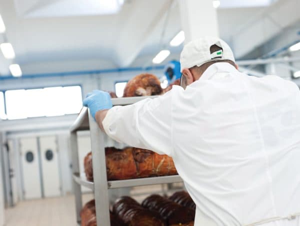 Operatore che spinge un carrello di porchette cotte verso la cella abbattitore