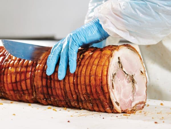 Porchetta tagliata a mano in tranci con il coltello